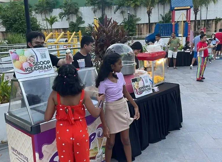 Food live station setup in Singapore featuring ice cream, popcorn and cotton candy carts at an outdoor family event by Innovative Event Concepts