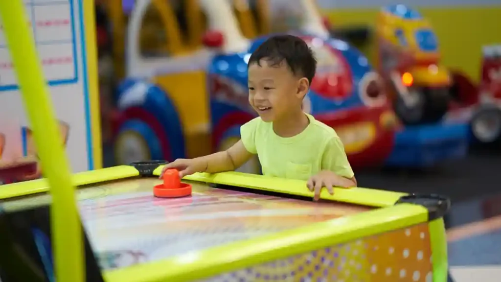 Child enjoying an air hockey game at an arcade machine rental setup for family events in Singapore