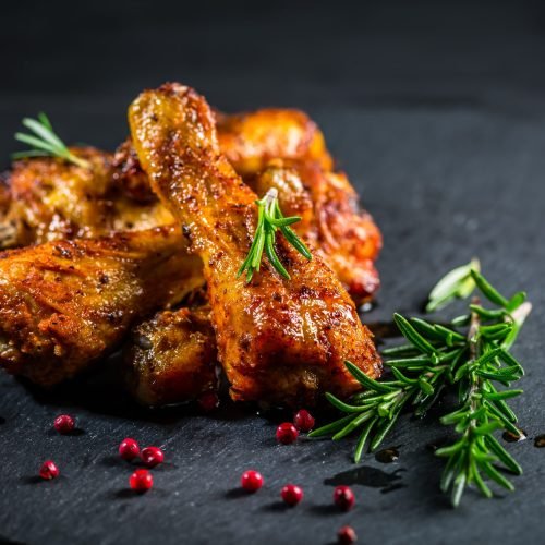 Oven baked chicken drumsticks with herbs and spicies on black background